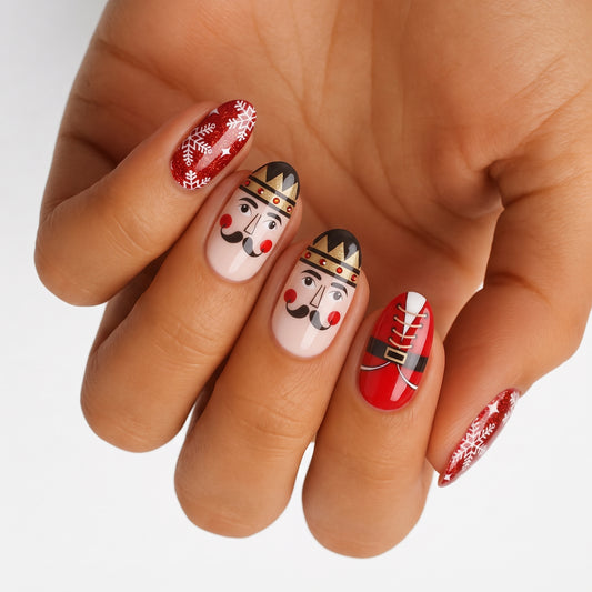 Nail wraps with nutcracker faces, red glitter snowflakes, and Santa belt design