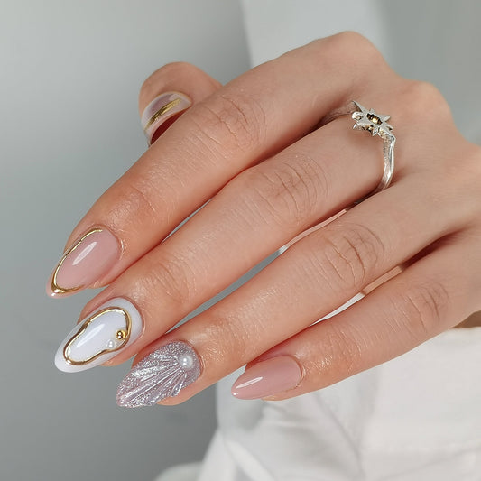 Glossy nude press-on nails with gold French tips, white swirl, pearl and shimmer shell accents
