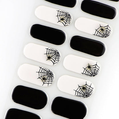 Semi-cured gel nail wraps, glossy black and white with black spiderweb and spider Halloween design.