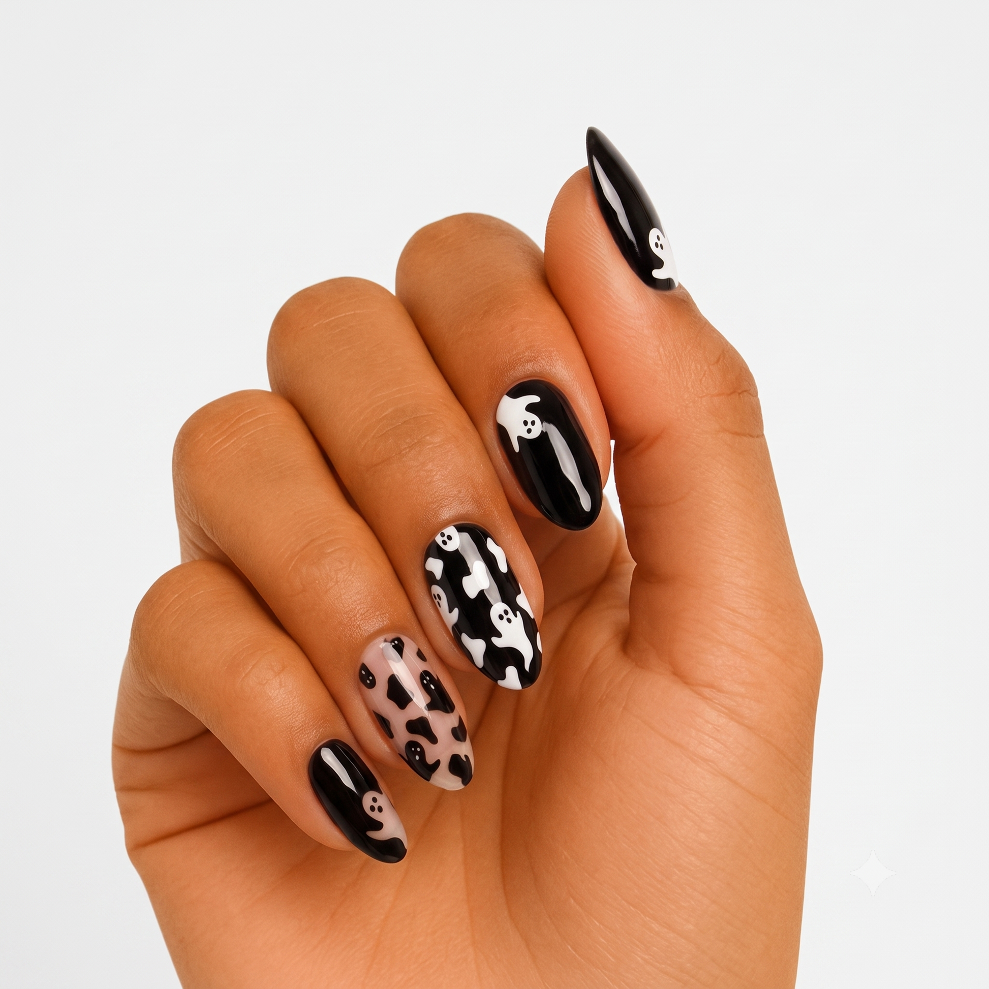 Glossy black press-on nails with white ghost print and nude cow-spot accent nail, Halloween design.
