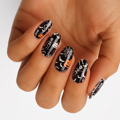 Black glossy nail wraps with white skeletons, orange pumpkins, spiderwebs and bats, Halloween design.