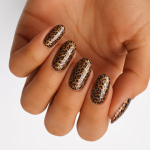 Glossy nail wraps in gold and black leopard print on almond-shaped nails