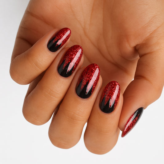Red glitter nail wraps with black flame-edge tips on an almond shape