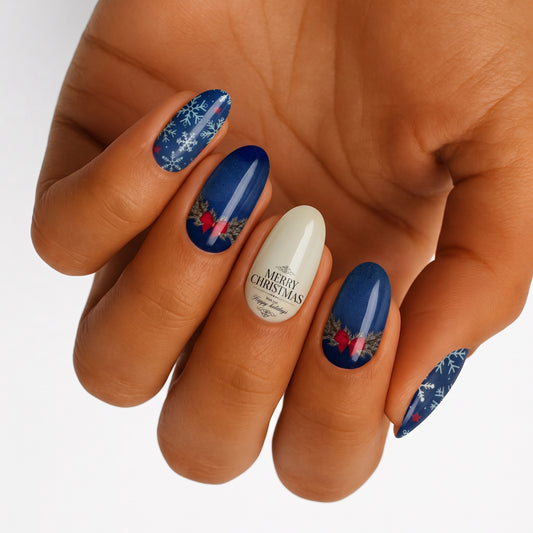 Navy blue nail wraps with snowflakes, red bows, wreaths, and "Merry Christmas" text on cream accent