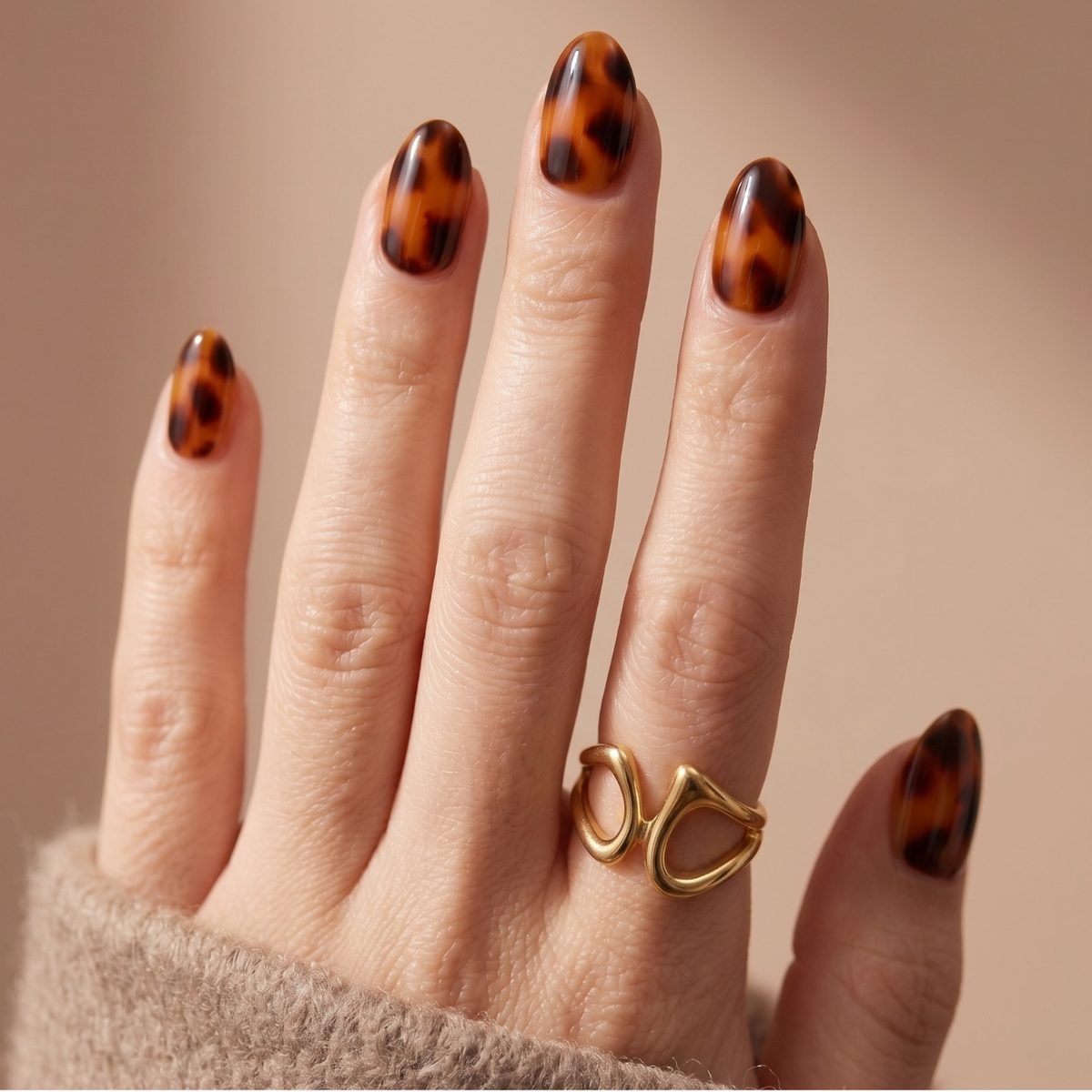 Glossy tortoiseshell nail wraps in amber and brown on almond-shaped press-on nails.