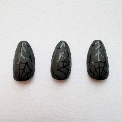 Glossy black almond press-on nails with tonal spiderweb Halloween design