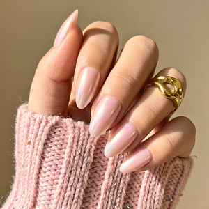 Pink chrome press-on nails with glossy mirror finish on hand wearing gold rings