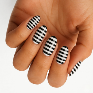 Glossy black and white striped nail wraps on an oval almond shape