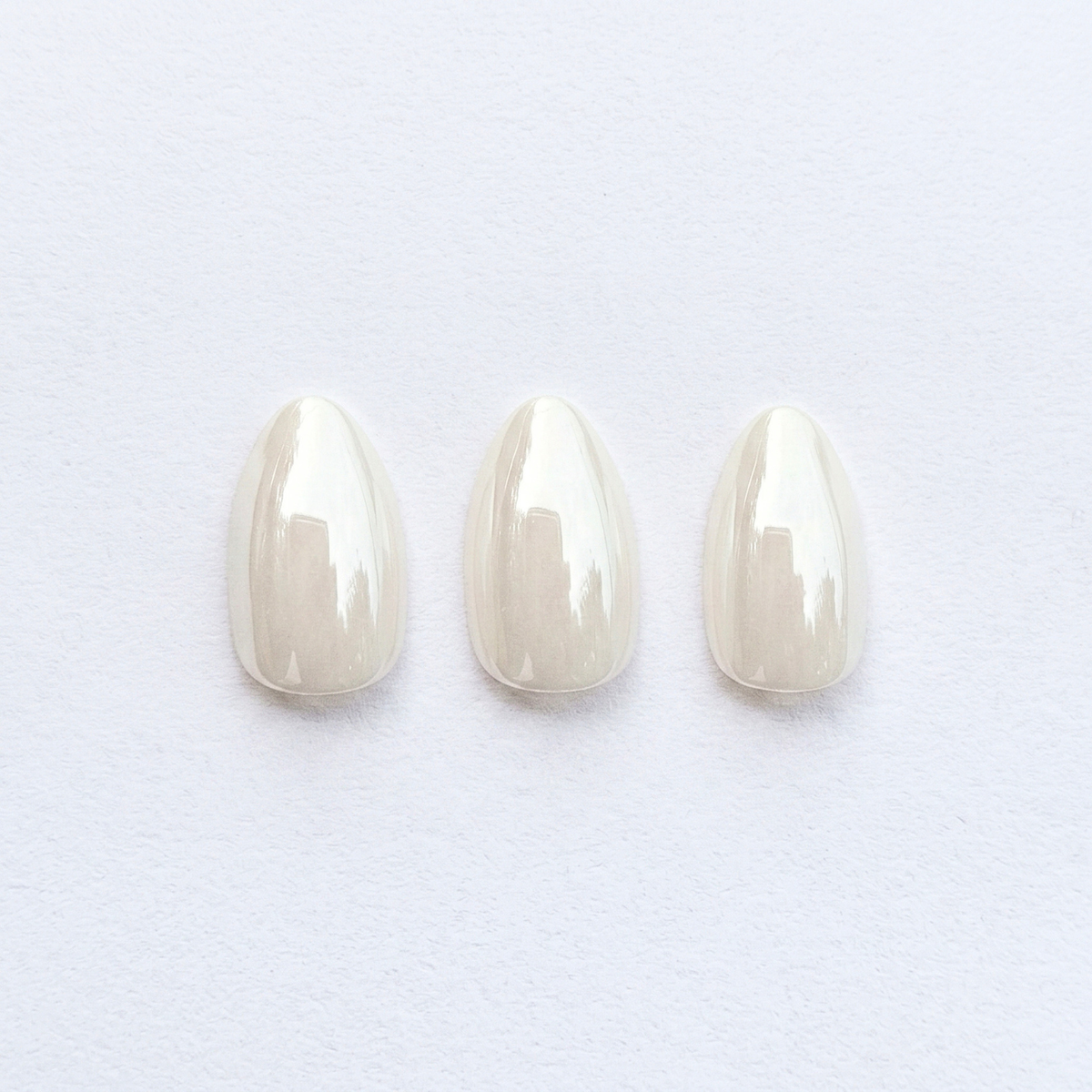 Sheer pearly white almond press-on nails with glossy, high-shine finish
