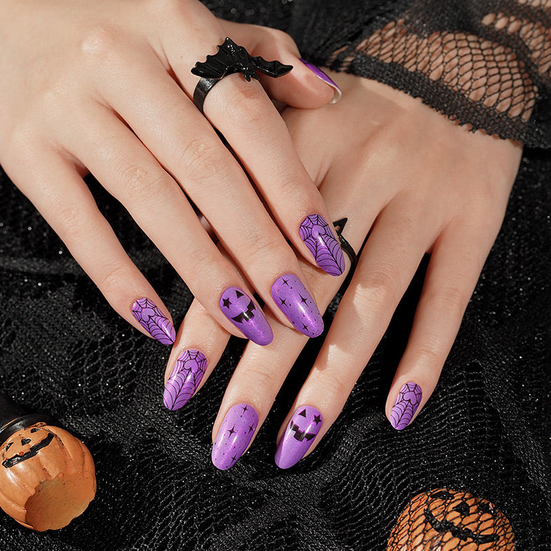 Purple press-on nails with black spiderweb, jack-o'-lantern, and star Halloween designs