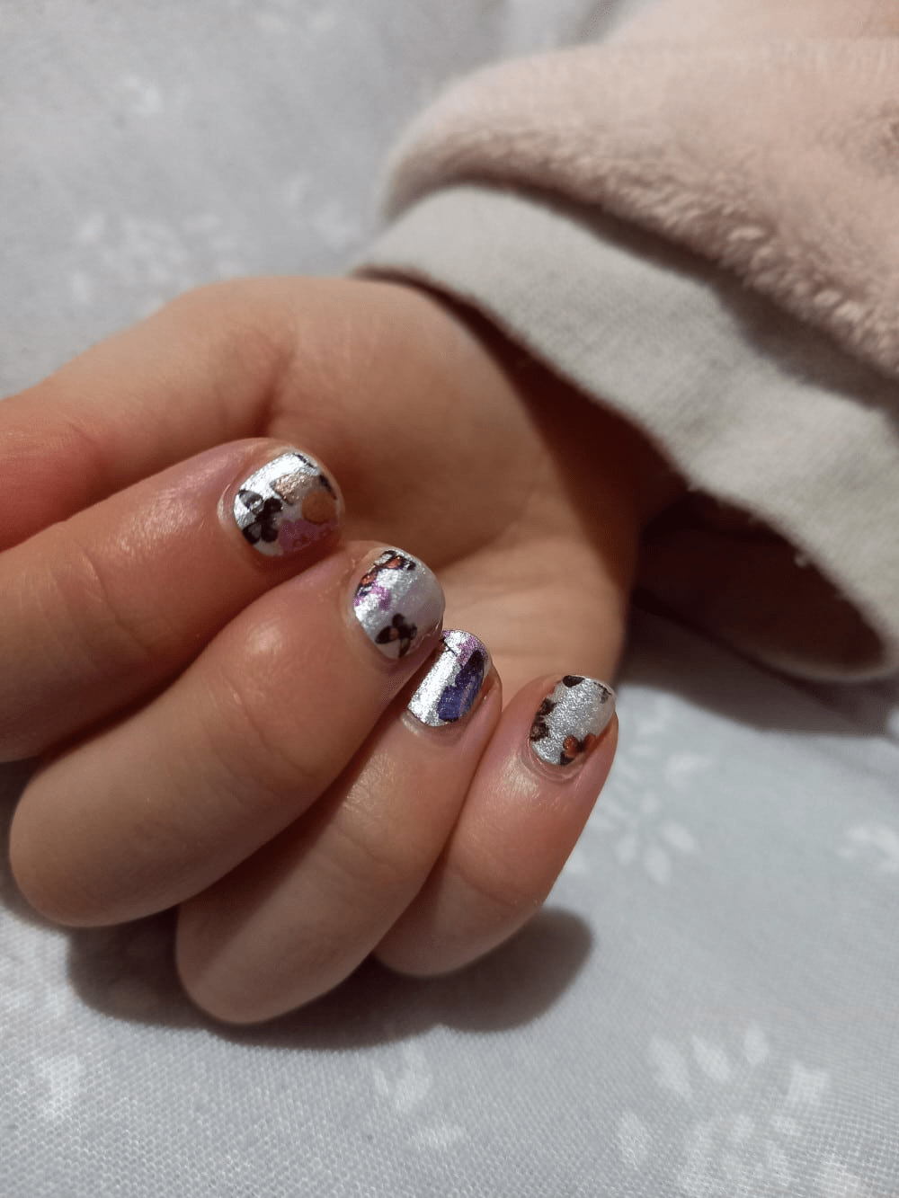 Child's hand wearing butterfly nail wraps with colourful butterfly nail art designs