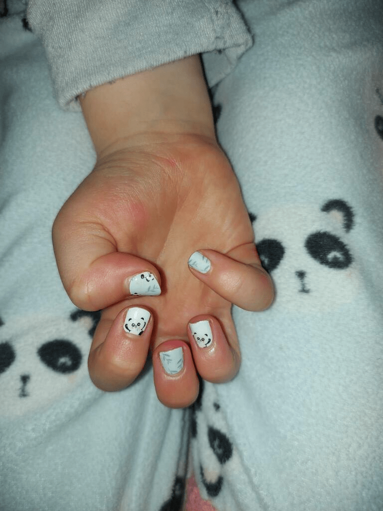 Child's hand wearing adorable panda gel nail wraps in pastel mint green with kawaii characters