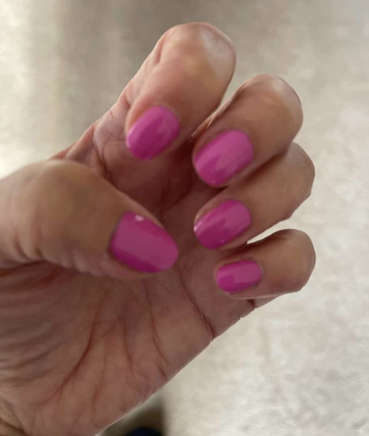 Bright hot pink glossy nail wraps on hand vibrant solid colour manicure