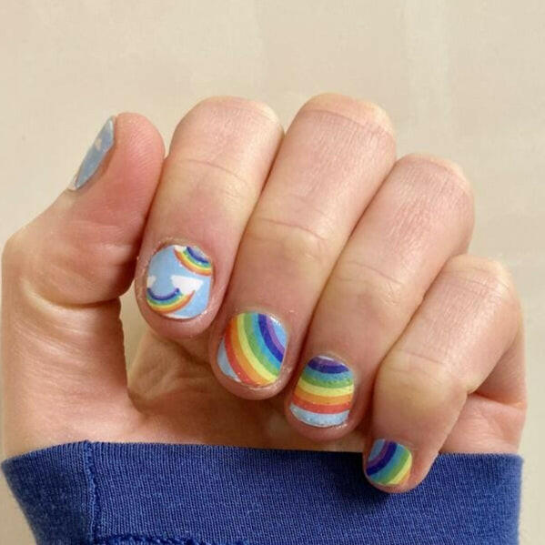 Hand wearing rainbow striped nail wraps with colourful geometric patterns for at-home manicure
