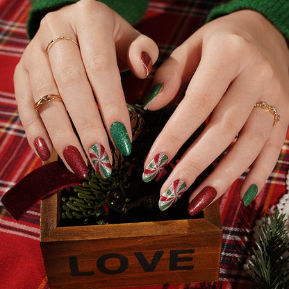 Hands wearing Christmas nail wraps with red and green glitter, candy cane swirl patterns for festive manicure