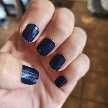 Deep navy blue nail wraps on hand showing glossy finish for DIY manicure