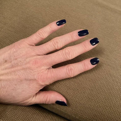 Hand displaying black glossy nail wraps with wide fit design for easy application