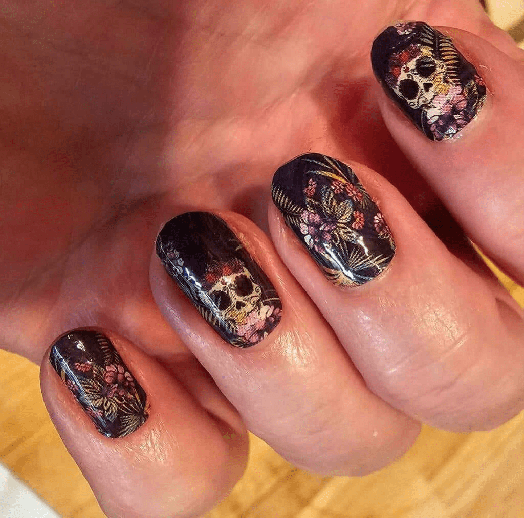 Gothic skull and floral nail wraps in dark purple tones on fingernails