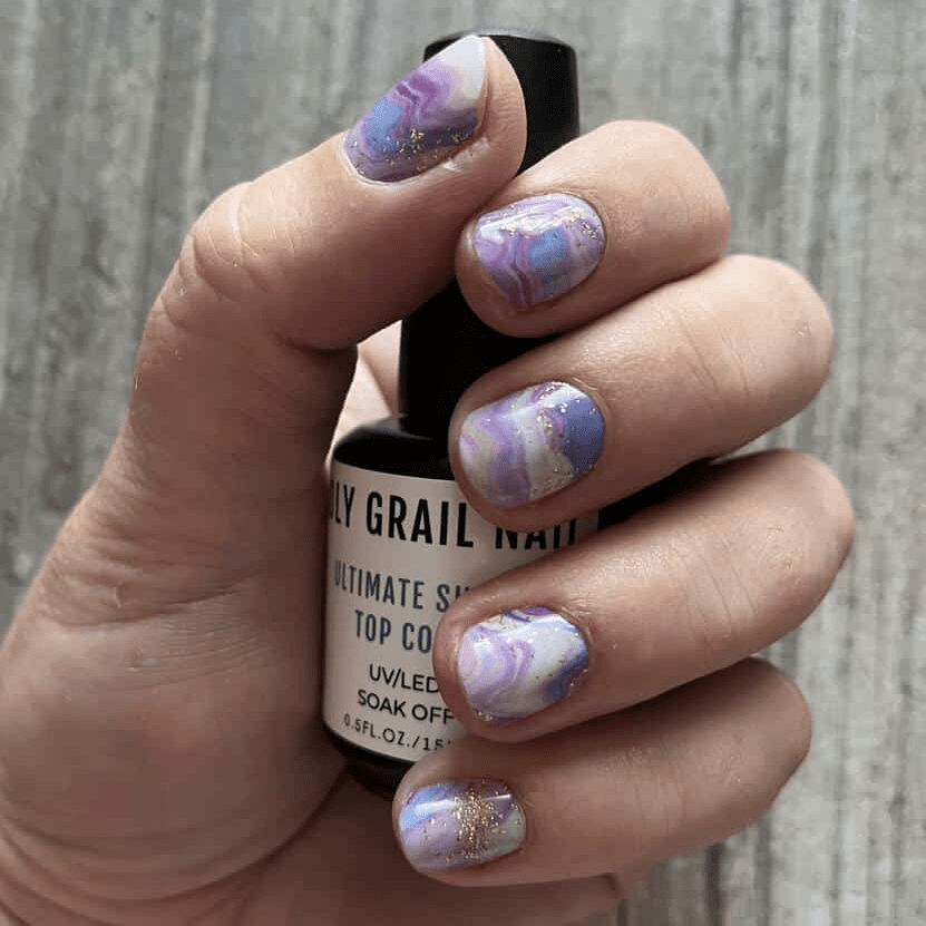 Purple marble nail wraps on hand holding bottle - amethyst stone pattern manicure
