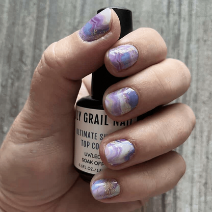 Purple marble nail wraps on hand holding bottle - amethyst stone pattern manicure