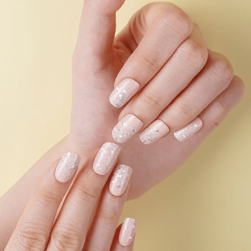 Pink nude glitter nail wraps on hands showing sparkly at-home manicure finish