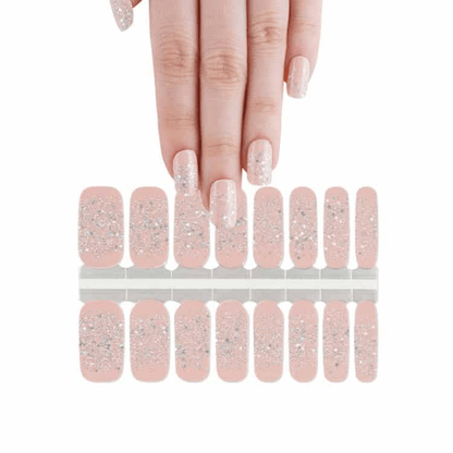 Pink nude glitter nail wraps sheet with hand showing applied manicure