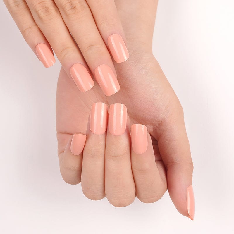 Overlapping hands showcasing peachy orange nail wraps with smooth glossy application