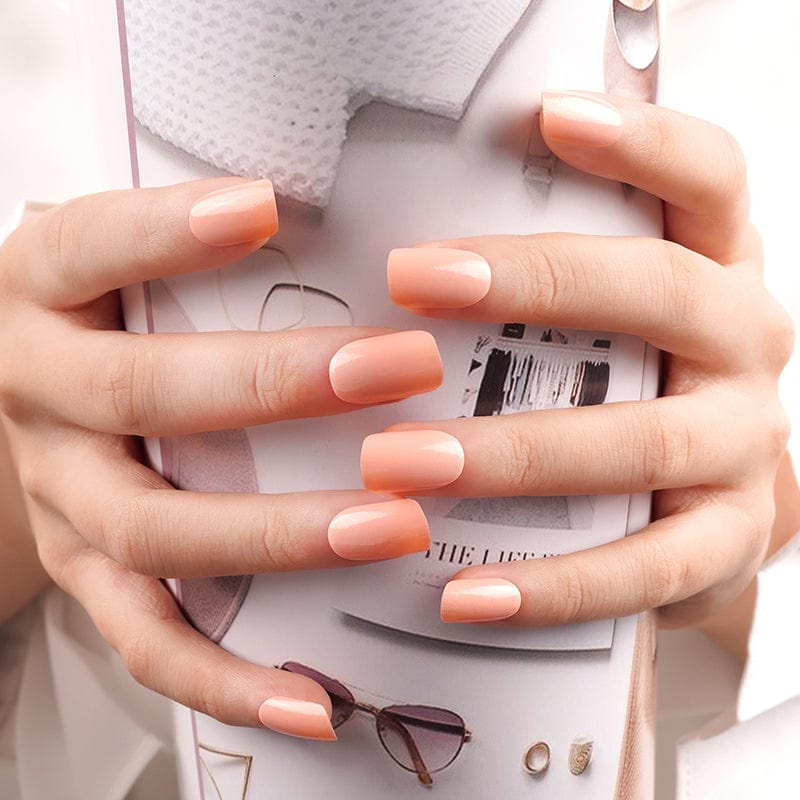 Hands wearing apricot orange solid colour nail wraps for at-home manicure