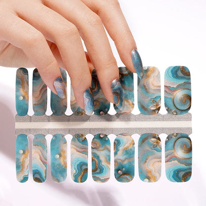 Hand applying teal marble nail wraps with gold accents to fingernails