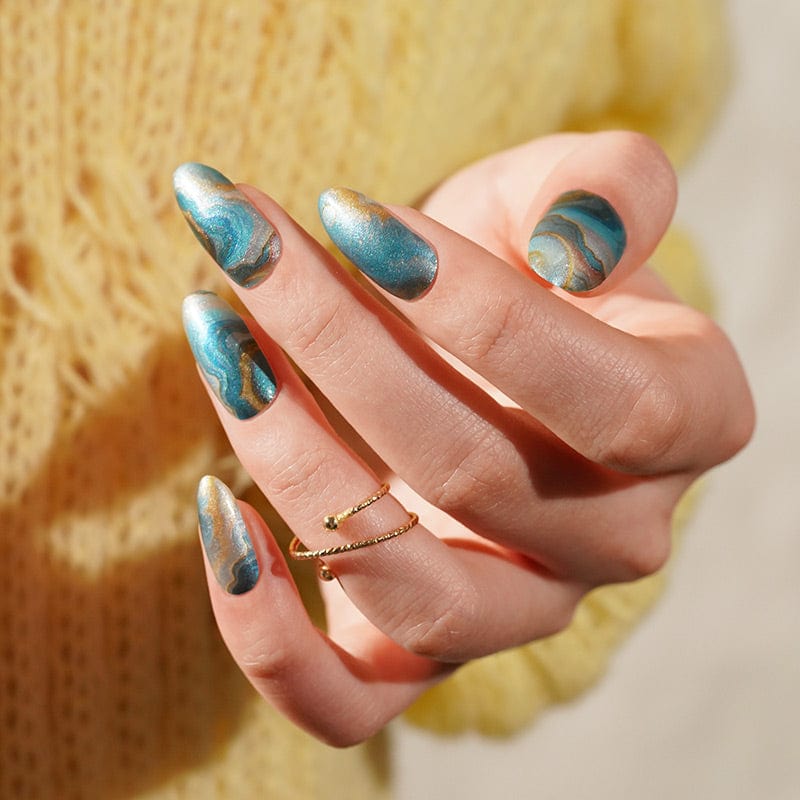 Aqua blue marble nail wraps with gold accents on manicured hand
