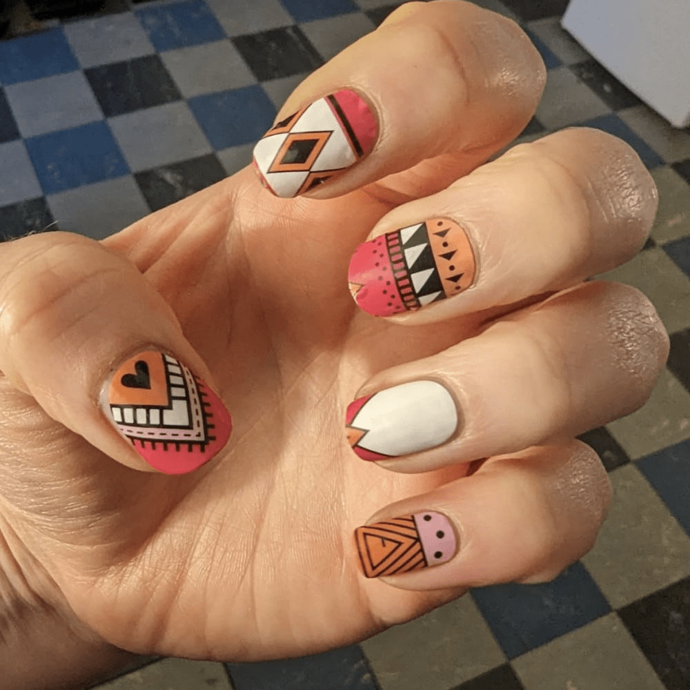 Aztec pattern nail wraps on hand with pink orange tribal geometric designs