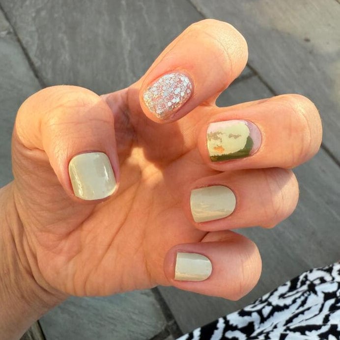 Sage green nail wraps with gold glitter accents on hand for elegant at-home manicure