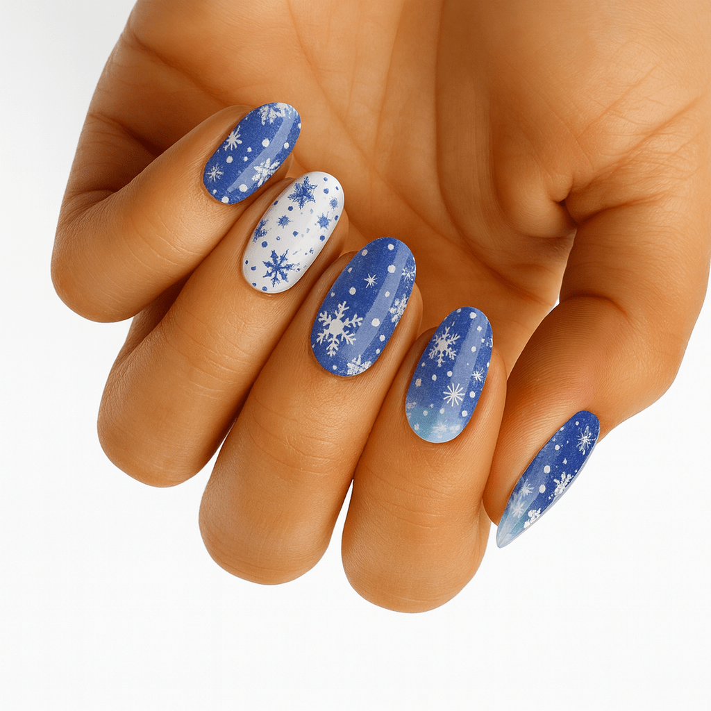 Blue winter nail wraps with white snowflakes on hand showing festive manicure design