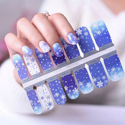 Winter snowflake nail wraps in blue gradient with hand holding wrap sheet