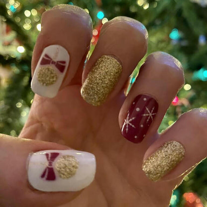 Festive Christmas nail art with burgundy and gold glitter nail wraps on hand