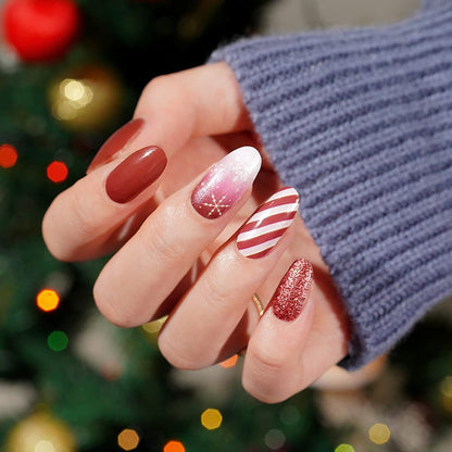 Red Christmas nail art on hand featuring glitter, candy cane stripes and snowflake designs