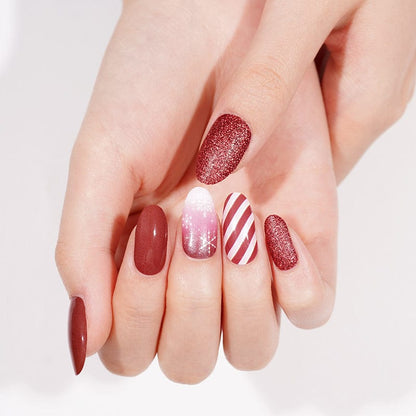 Festive manicure with red glitter, burgundy and white striped Christmas nail wraps on hand