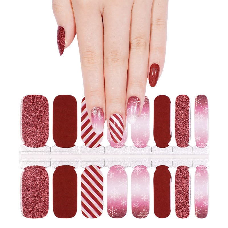 Hand wearing burgundy and pink Christmas nail wraps with glitter and striped patterns