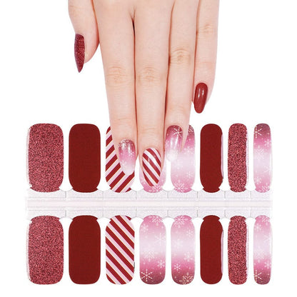 Hand wearing burgundy and pink Christmas nail wraps with glitter and striped patterns