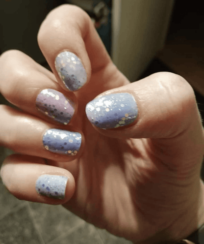 Hand wearing blue purple ombre glitter nail wraps with holographic sparkle confetti design