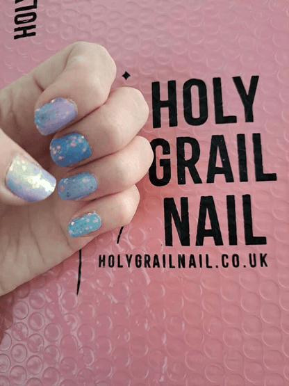 Hand modelling pastel blue purple nail wraps with iridescent glitter at-home manicure
