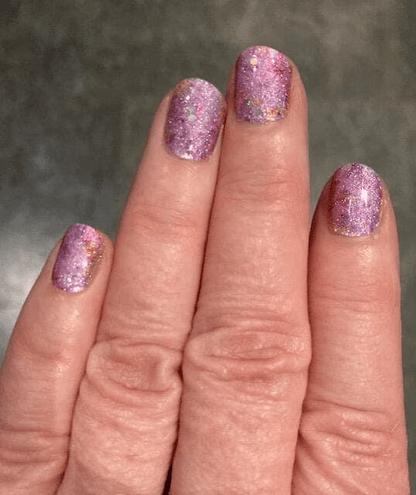 Pink glitter nail wraps on hand creating sparkly manicure with holographic finish