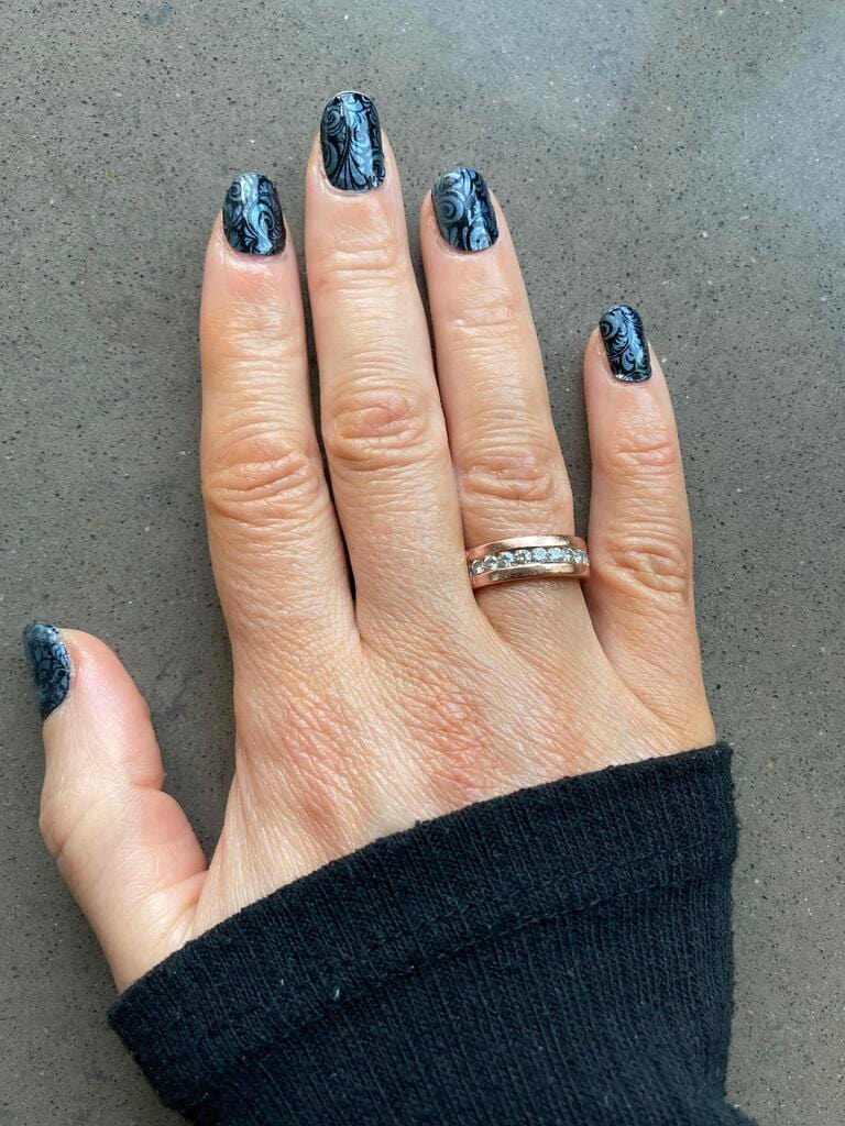 Dark gothic nail art wraps with blue accents displayed on female hand