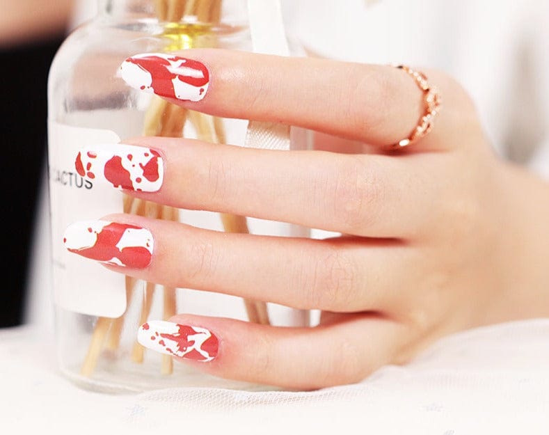 Hand holding glass showing red blood splatter nail art wraps design
