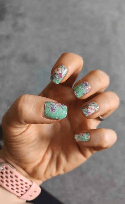 Green floral nail wraps with pink flowers on hand showing at-home manicure nail art
