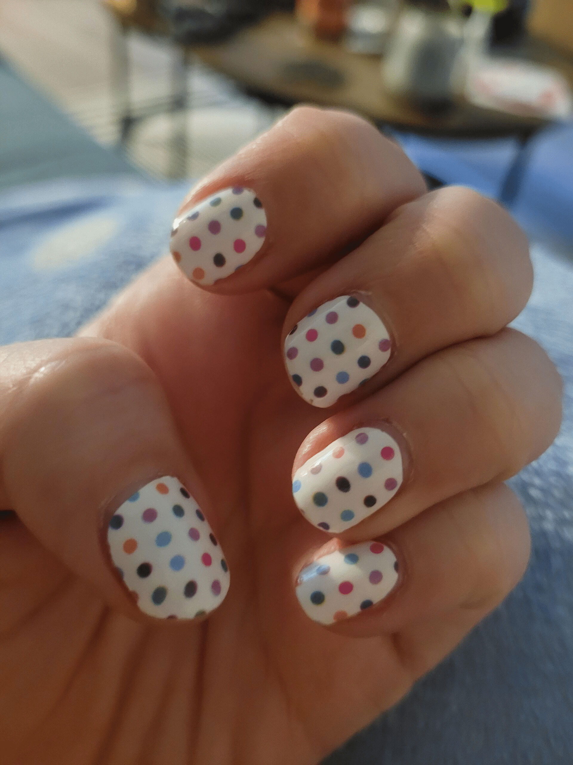 White nail wraps with colourful polka dots on hand showcasing classic manicure design