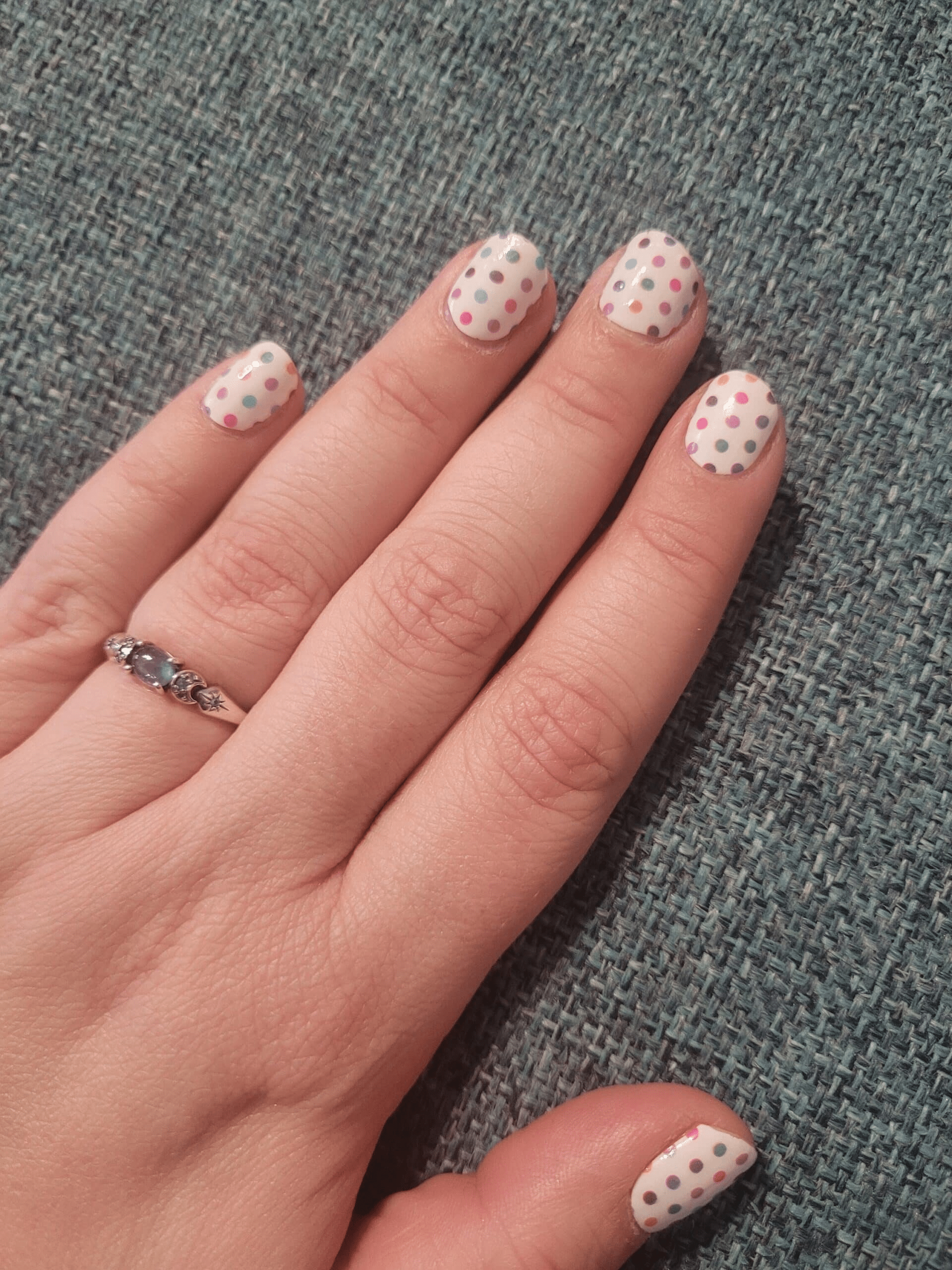 White nail wraps with pink polka dot pattern on hand for classic spotted manicure design
