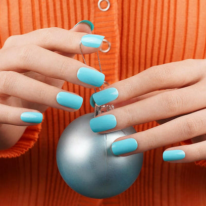Turquoise blue gel nail wraps on hands holding metallic ornament for festive manicure look