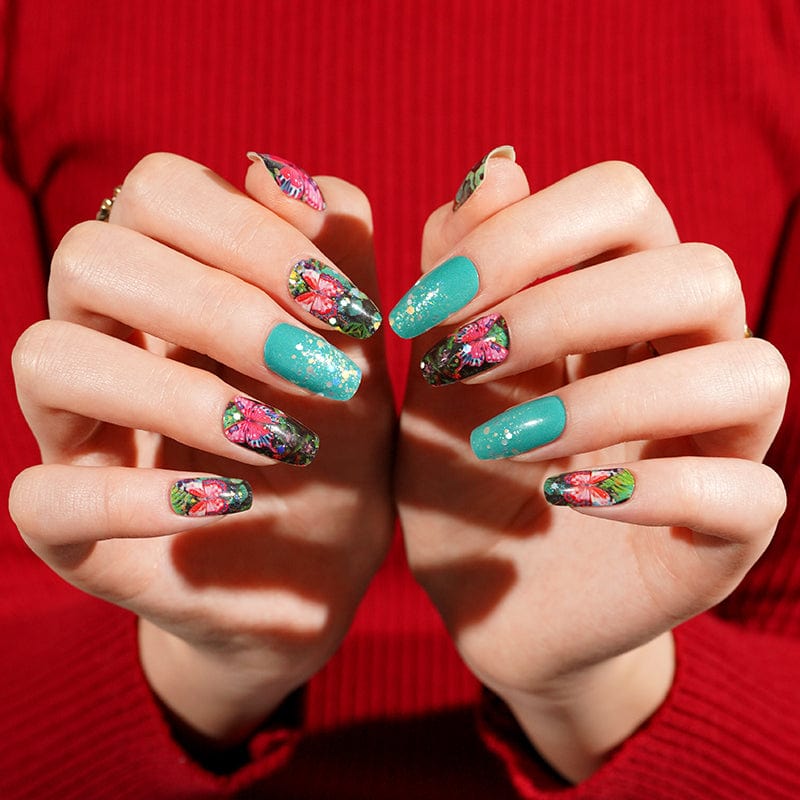 Vibrant floral nail wraps on hands showing botanical garden pattern with butterfly motifs