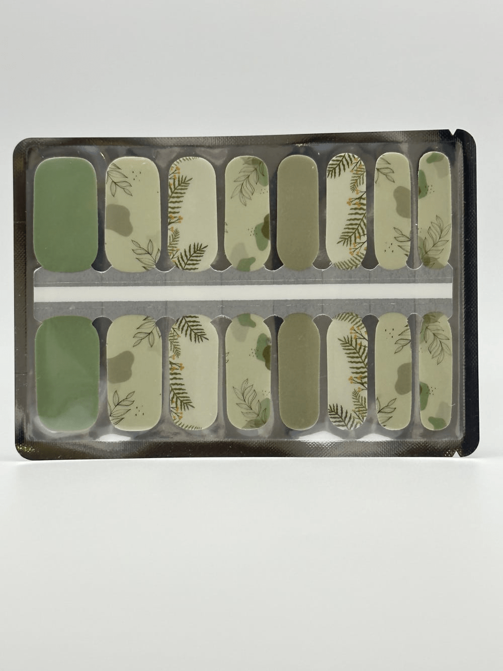 Green botanical leaf pattern nail wraps displayed in packaging showing nature-inspired nail art design
